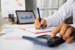 Close up hand of business man pressing on calculator to check on financial income and profit