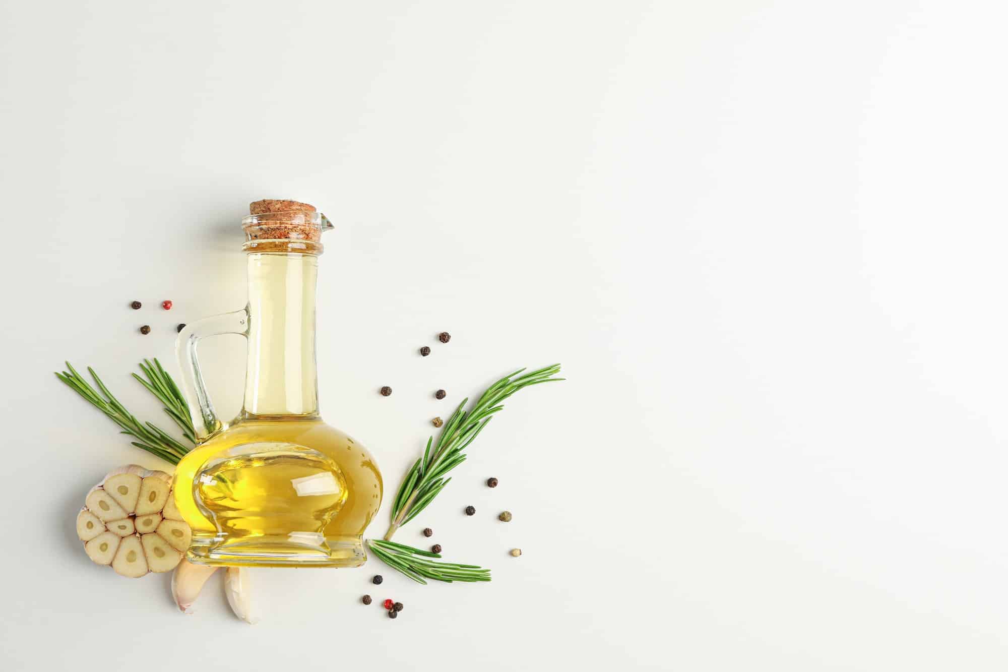 Rosemary oil and leaves, garlic, pepper on white background, top view